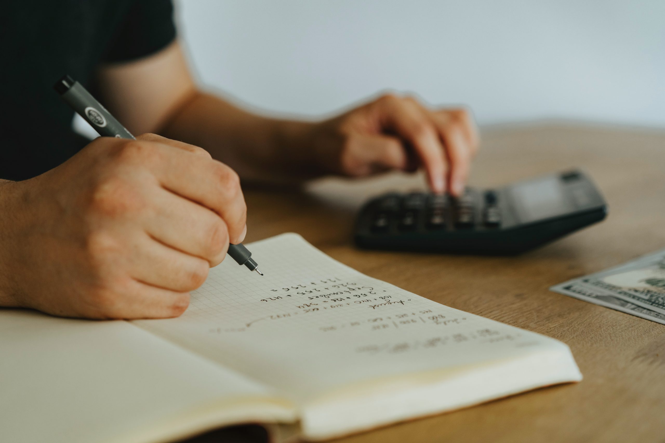 Financial Planners Brisbane - Person writing in book with calculator